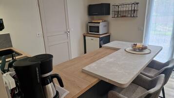 Een moderne keuken met een houten aanrecht, een koffiezetapparaat, een magnetron en een televisie op een plank.