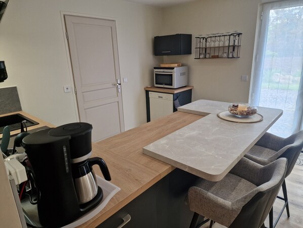 A modern kitchen with a wooden countertop, a coffee maker, a microwave, and a TV on a shelf.