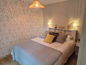 A neatly made bed with a grey blanket, a wooden headboard, and two bedside lamps.