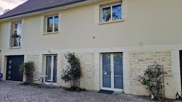 Un bâtiment à deux étages, doté d’une façade en pierre, d’un toit en tuiles et d’une cour pavée.