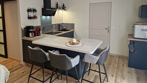 Eine kompakte Küche mit einer zentralen Kochinsel, Barhocker, einer Kaffeemaschine und einer Mikrowelle.