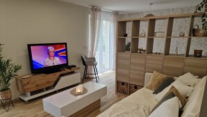 Ein modernes Wohnzimmer mit Fernseher, Sofa, Couchtisch und einem Holzschrank.