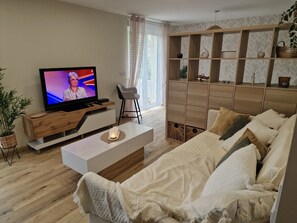 Un salon moderne comprenant un téléviseur, un canapé, une table basse et un meuble en bois.