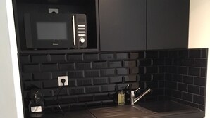 Cozinha moderna com armários pretos, micro-ondas e pia.