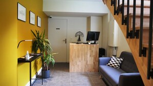 Um espaço moderno para viver, com um balcão de recepção em madeira, um sofá azul e uma escada.