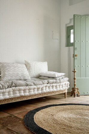 A room with a bed, a green door, and a patterned rug. - Alojamiento Rural CASAPIÑA (Conil de la Frontera)