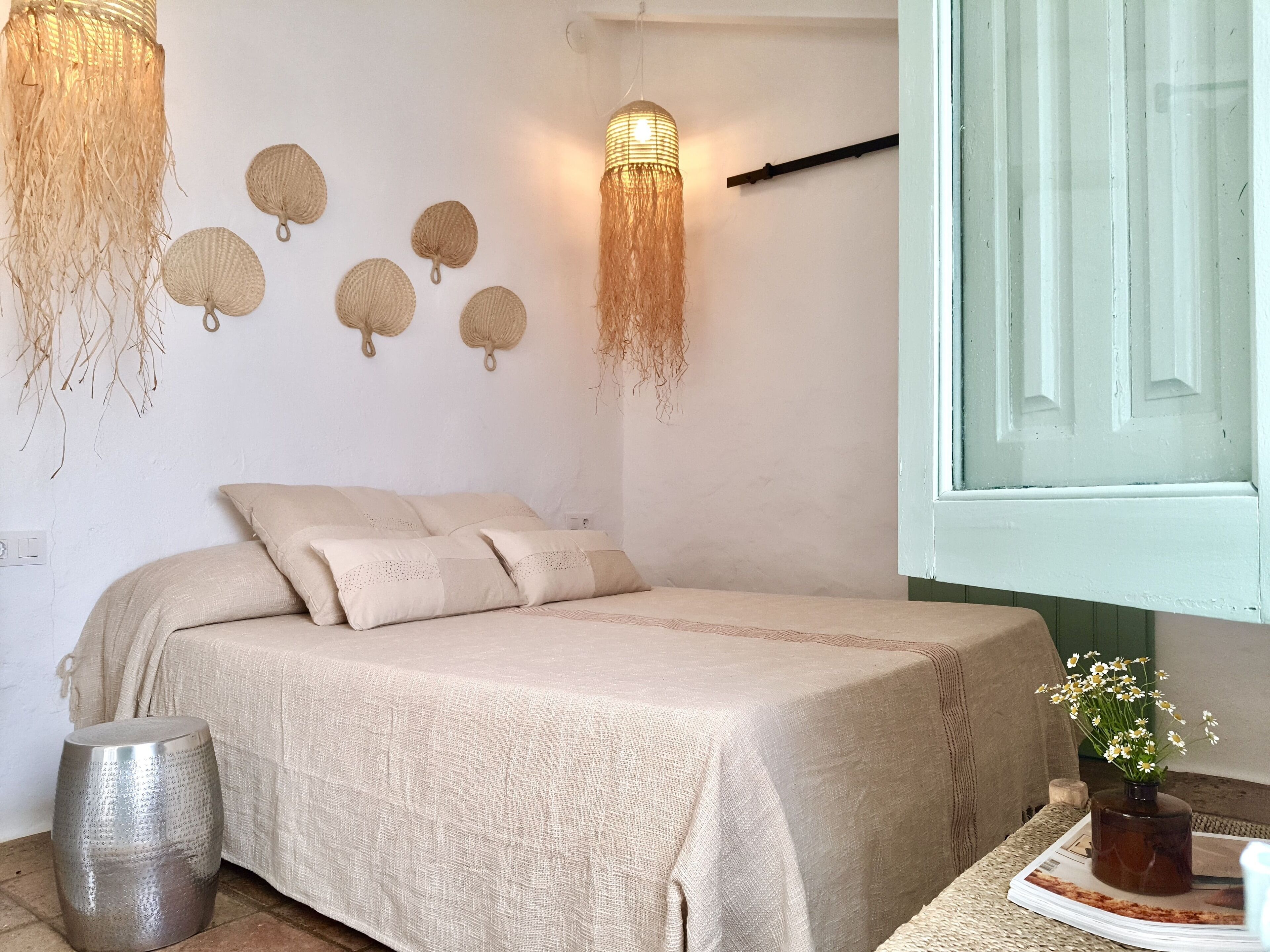 Ein Schlafzimmer mit einem Bett, einem Nachttisch mit einer Vase und Wanddekoration.