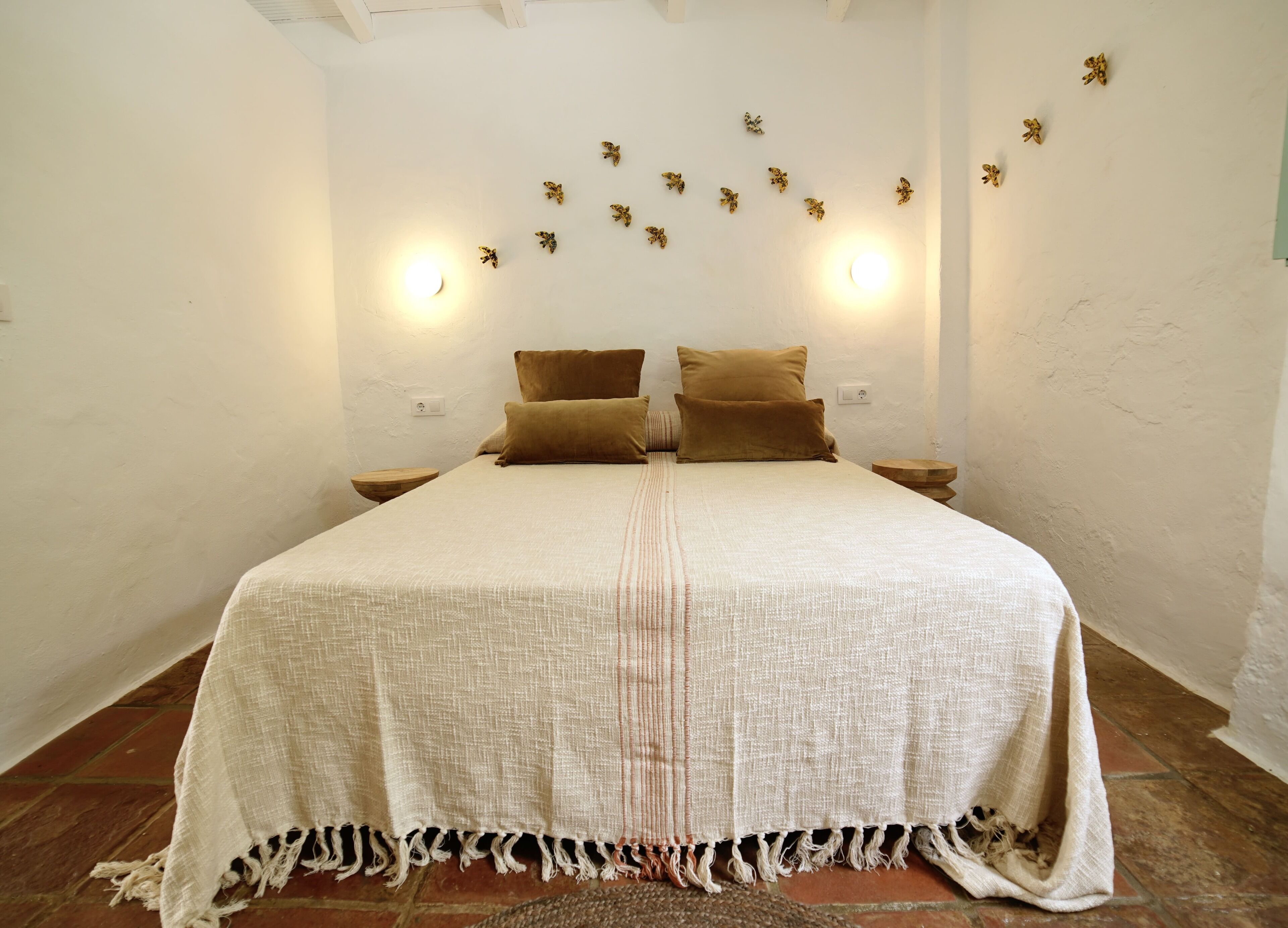 A bedroom with a large bed, two nightstands, and wall-mounted lights.