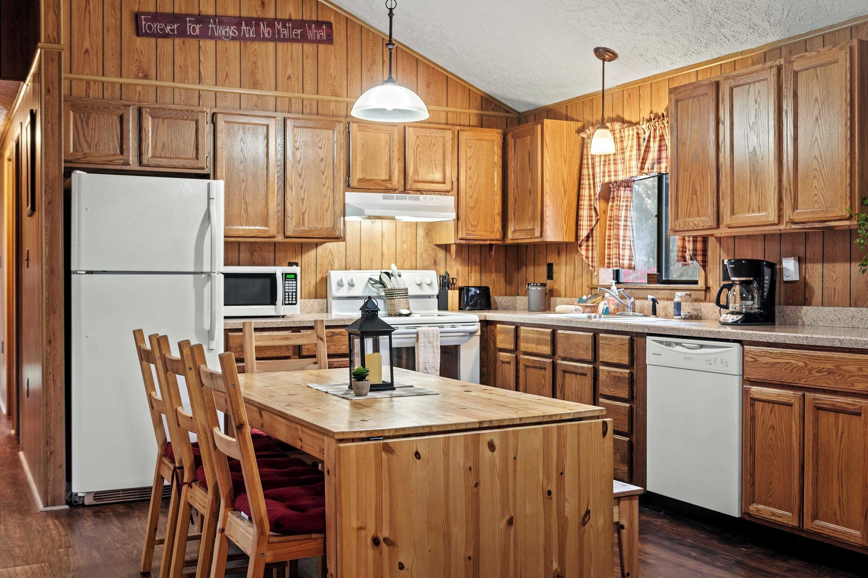 Une cuisine avec des meubles de rangement en bois, un réfrigérateur blanc, un four à micro-ondes, une cuisinière, un évier et une table à manger avec des chaises.