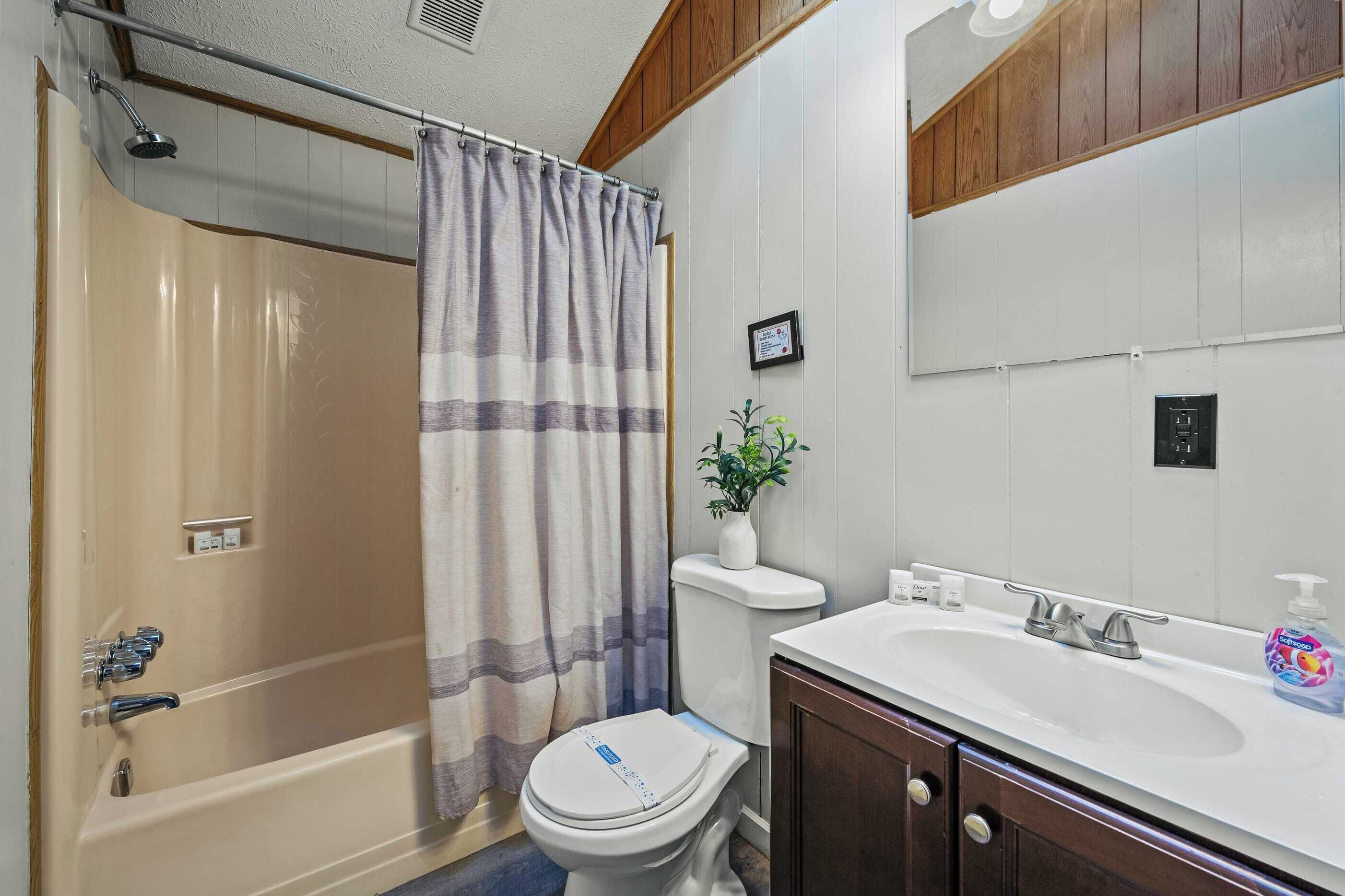 Un baño con ducha, inodoro, lavabo y espejo.