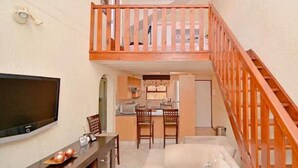 A compact living space with a kitchen area, a dining table, and a TV.