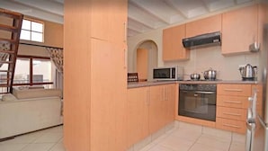 A kitchen with wooden cabinets, a microwave, an oven, and a window with curtains.