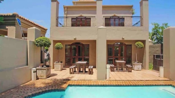 A two-story house with a swimming pool, outdoor furniture, and a balcony.