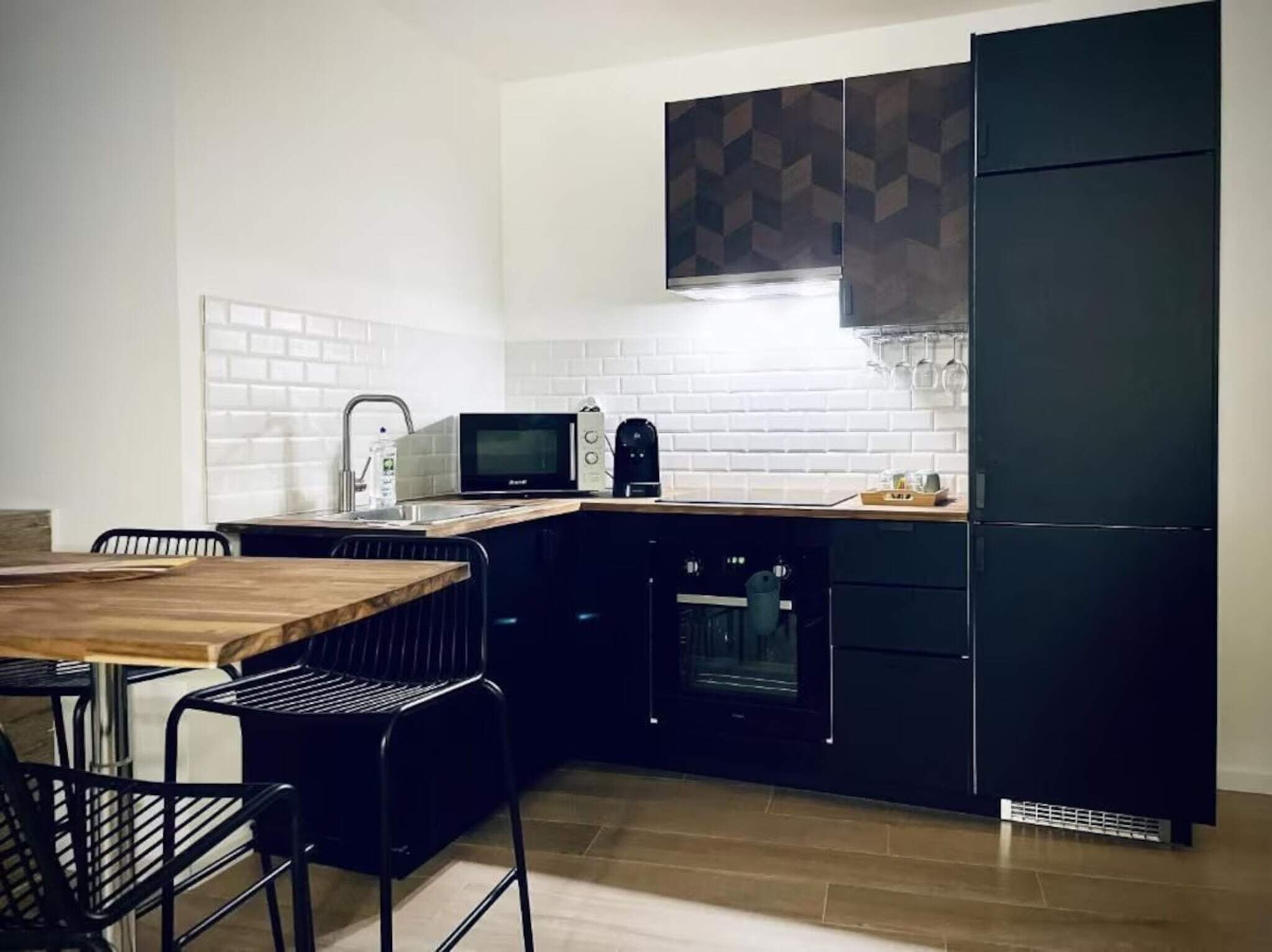 Une cuisine de taille réduite équipée d’un four à micro-ondes, d’un four traditionnel et de meubles de couleur noire.