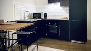 Une cuisine de taille réduite équipée d’un four à micro-ondes, d’un four traditionnel et de meubles de couleur noire.