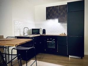 A compact kitchen with a microwave, oven, and black cabinets.