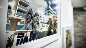 Vue par une fenêtre sur un immeuble moderne doté de balcons et d’un palmier.