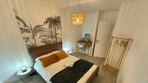 Une chambre à coucher bien rangée, avec un lit, une table de chevet, une lampe et une fresque murale.