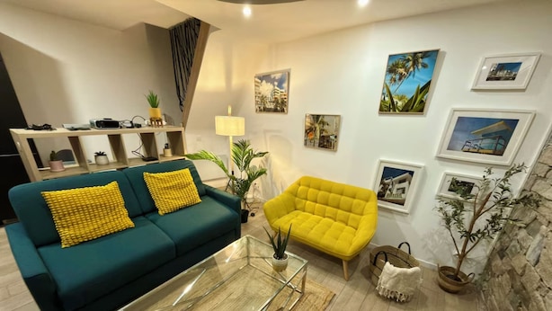 Un salon comprenant un canapé, un fauteuil, une table basse et des œuvres d’art murales.