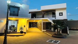 Un bâtiment moderne doté d’une entrée bien éclairée, d’un balcon et d’une enseigne indiquant l’emplacement du hall d’accueil.
