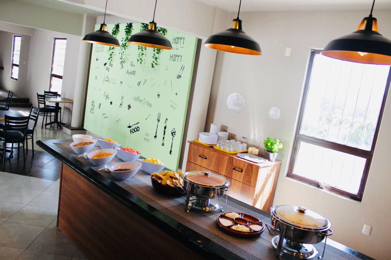 Una zona de cocina con espacio tipo bufé, que incluye fuentes de comida, una olla caliente y una exposición de frutas.