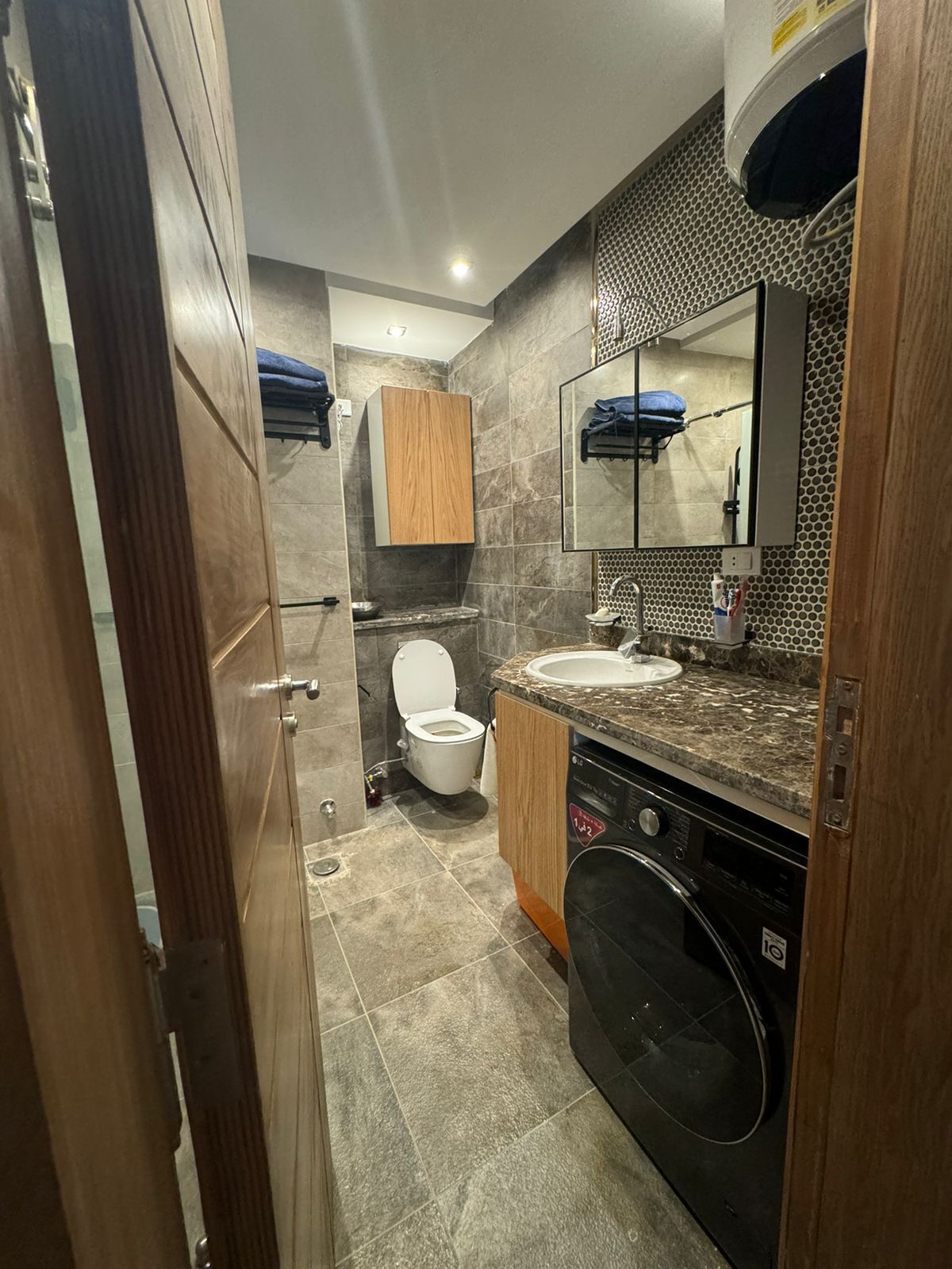 Une petite salle de bain comprenant des toilettes, un lavabo et un lave-linge.