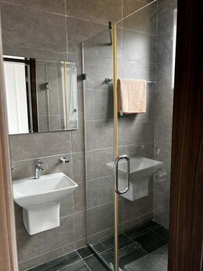 Enjoy a refreshing shower in the bathroom, featuring a glass-enclosed shower and separate sink with a faucet.