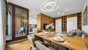 Een moderne woonkamer met een houten eettafel gedekt voor vier personen, een bank en een televisie.