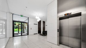 Een moderne lobby met een strak betegelde vloer, een zithoek en een lift.
