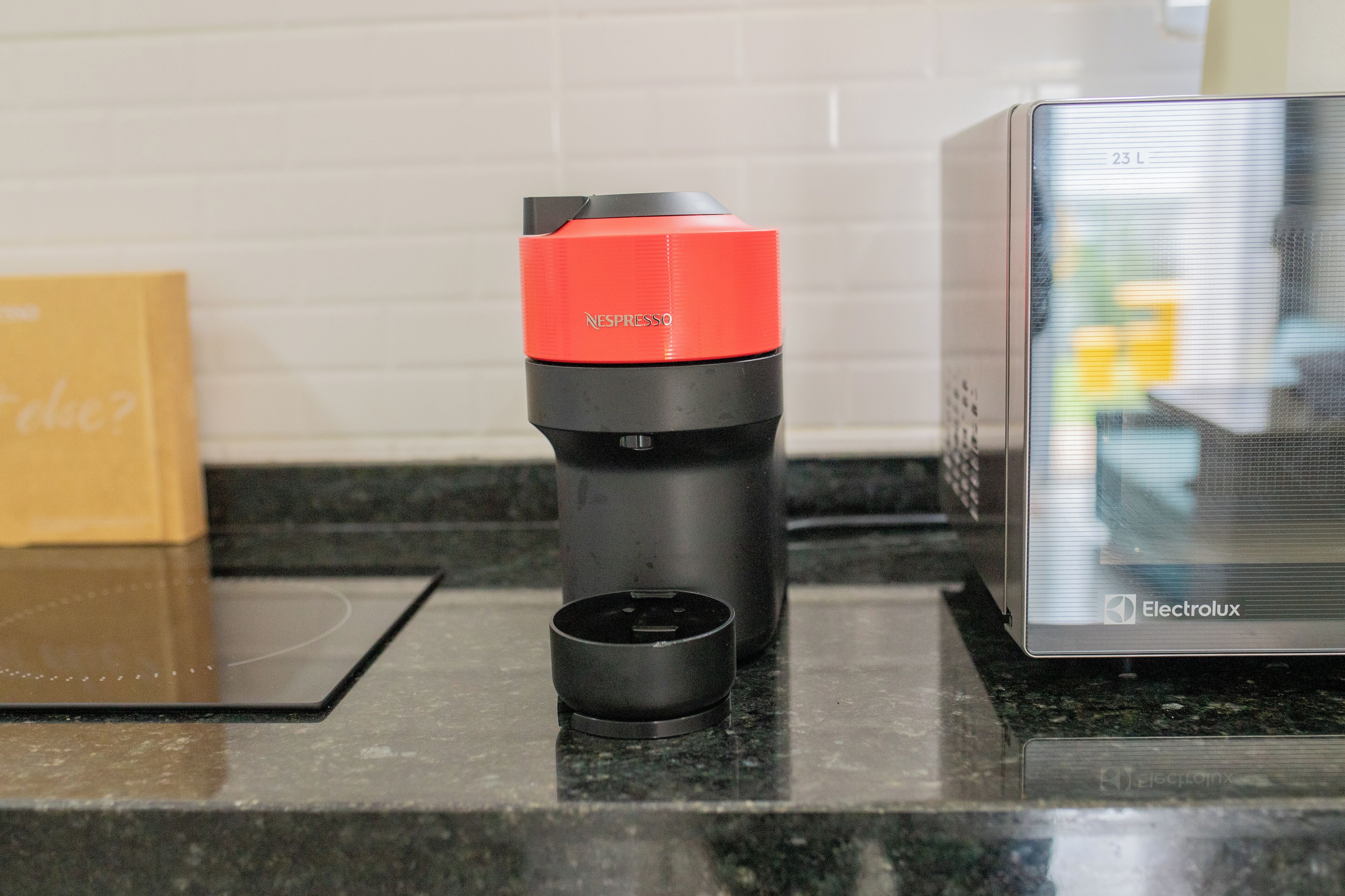 A kitchen counter with a coffee machine, a black cup, and a box.