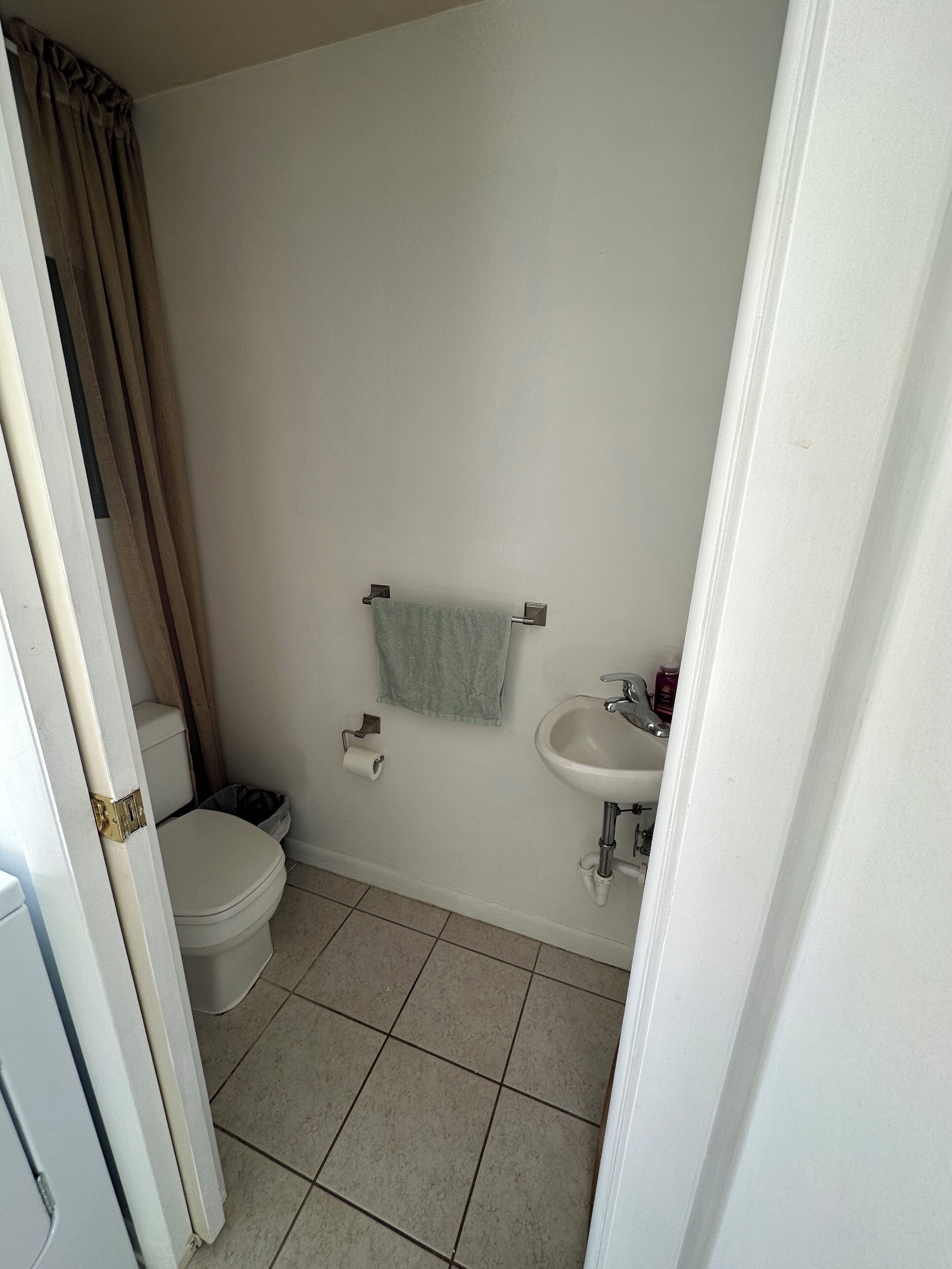Un baño con inodoro, lavamanos y una toalla colgada en la pared.