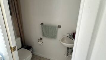 Un baño con inodoro, lavamanos y una toalla colgada en la pared.