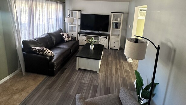 Ein Wohnzimmer mit einer Couch, einem Couchtisch, einem Fernseher und einer Lampe.