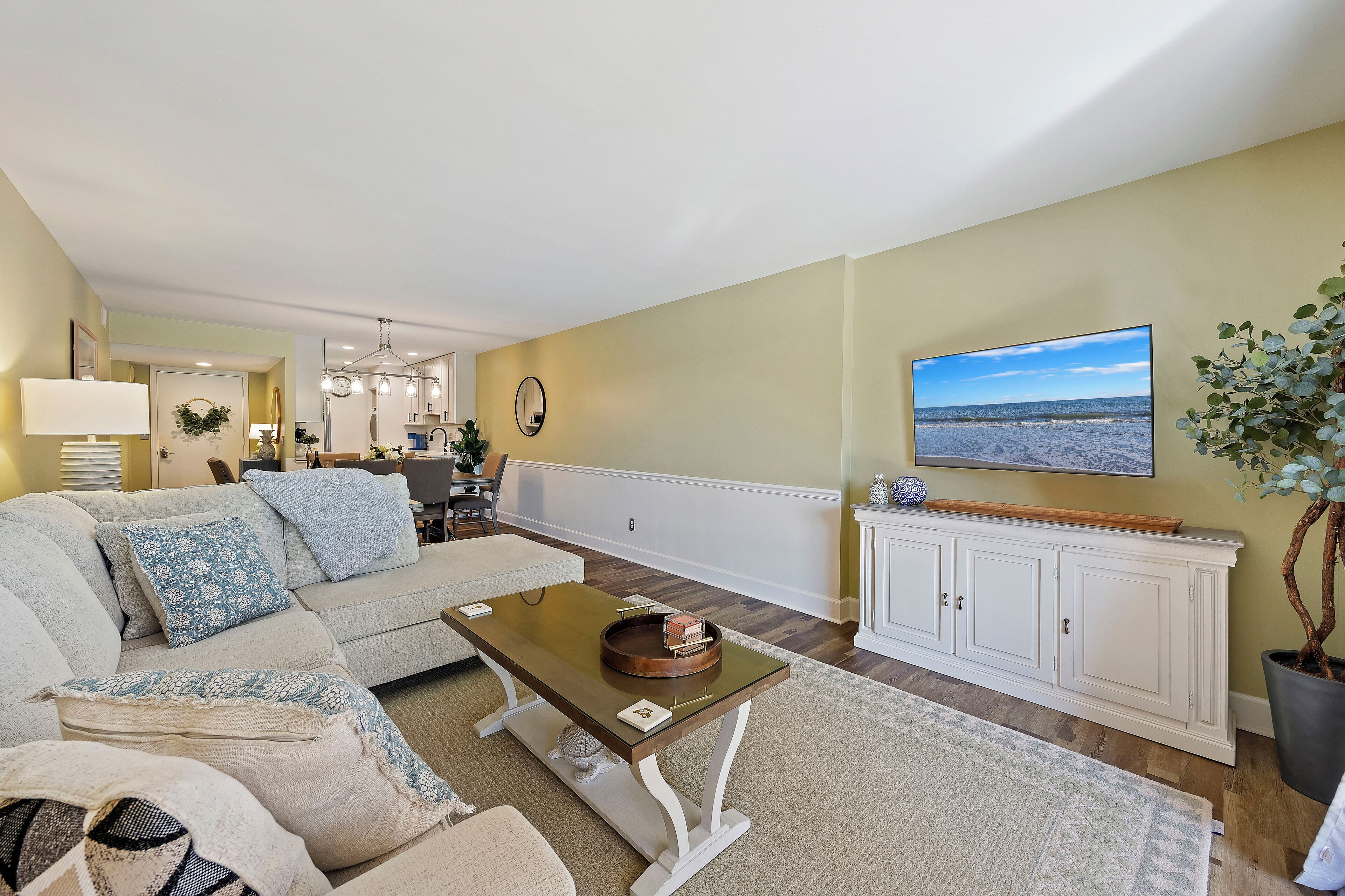 A living room with a sofa, coffee table, and a TV mounted on the wall.