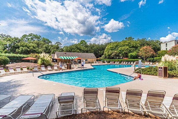 A swimming pool with lounge chairs and a building with a green roof.