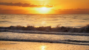 Ein Strand mit Wellen und einem Sonnenuntergang.