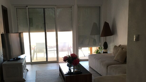 A living room with a sofa, a coffee table with flowers, a lamp, and a television.