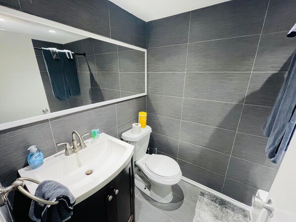 Casa de banho moderna com uma sanita, um lavatório branco e um espelho grande.