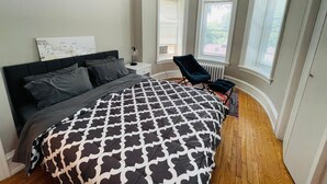 A bedroom with a bed, a chair, and two windows. - Charming Place to Call Home (Elkins Park)