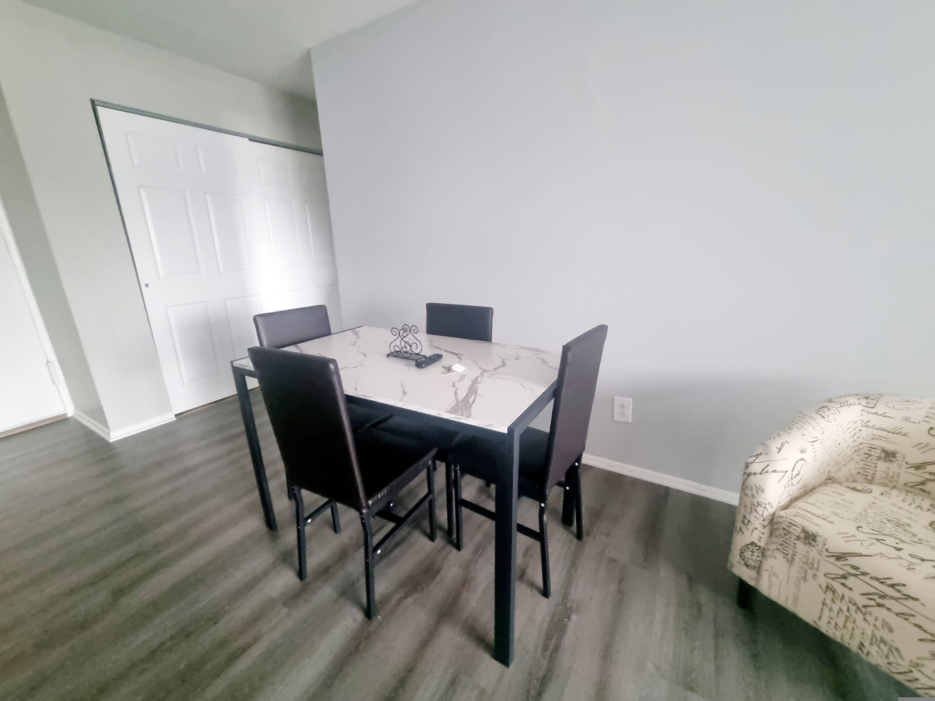 Un coin repas avec une table blanche et quatre chaises noires.