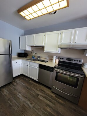 A modern kitchen with white cabinets, stainless steel appliances, and a wooden floor. - Fully Furnished 1BR Near Mossrehab (Elkins Park)