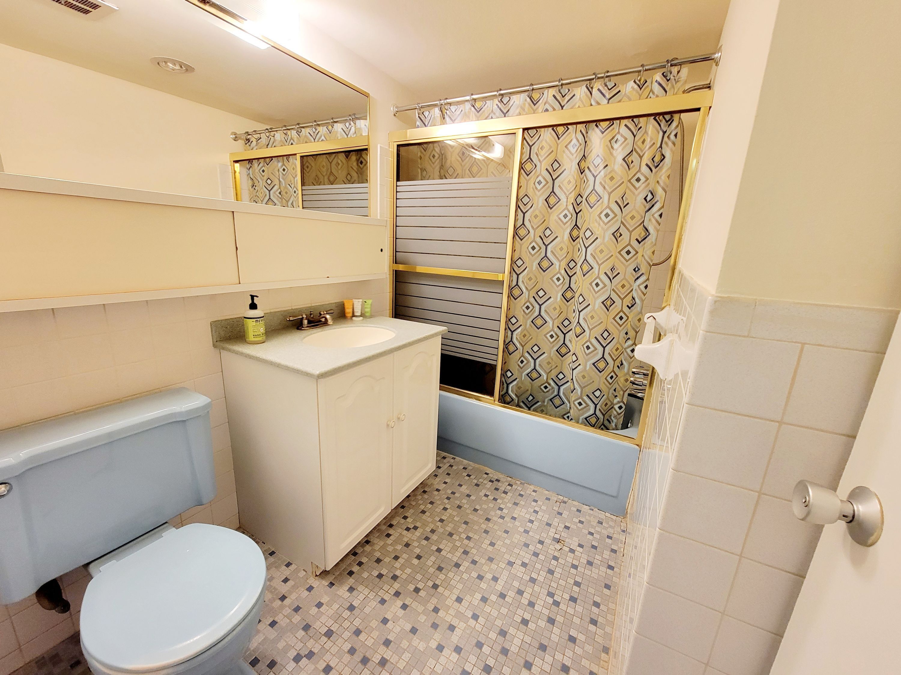 Et badeværelse med toilet, vask og bruseområde.