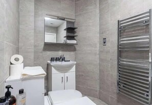 Un baño moderno con lavamanos, espejo y toallero blancos.