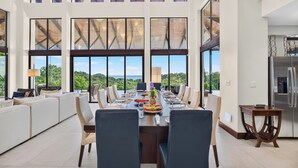A spacious dining area with a long table, multiple chairs, and a view of the outdoors.