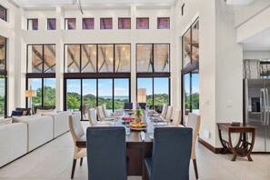 A spacious dining area with a long table, multiple chairs, and a view of the outdoors.