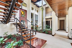A modern interior with a spiral staircase, indoor plants, and a wooden ceiling.