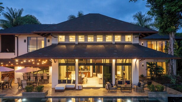 A modern house with a swimming pool, outdoor seating, and a covered patio area.