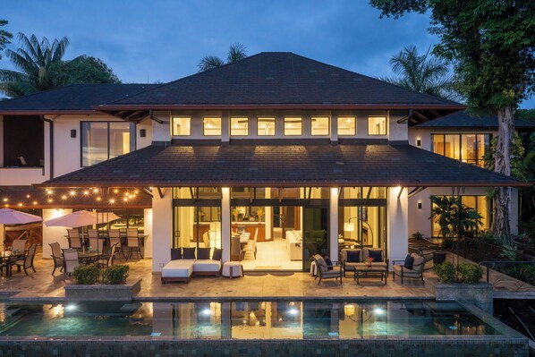 A modern house with a swimming pool, outdoor seating, and a covered patio area.