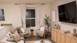 Una sala de estar moderna con un sofá, sillones, una mesa de centro y un televisor montado en la pared.