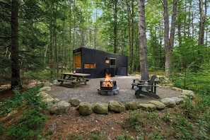 A cabin with a fire pit and picnic table surrounded by rocks. - Postcard Cabins Asheboro, Outdoor Collection by Marriott Bonvoy (Asheboro)